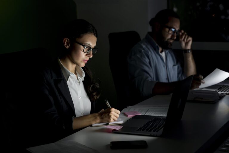 Two professionals working late at night reviewing audit files during busy season